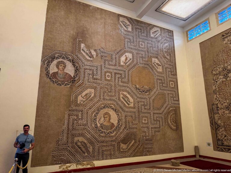 Large Roman mosaic with interlocking geometric bands, portrait medallions, and small motifs in compartmented panels.