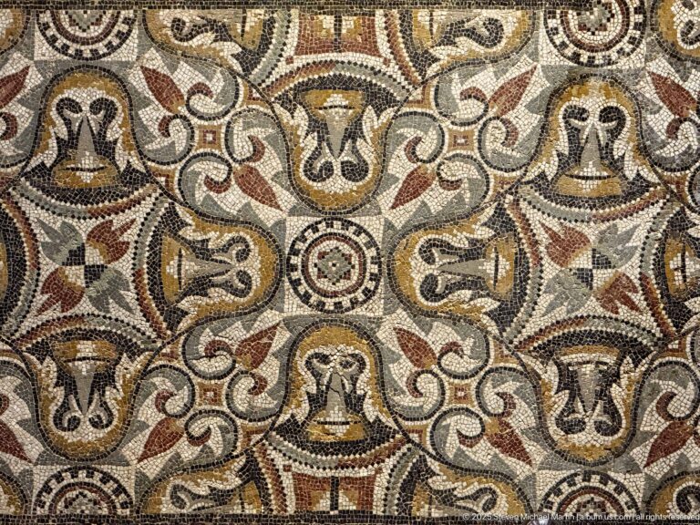 Polychrome Roman mosaic with repeating vase-like motifs, scrolling bands, circular rosettes, and red, yellow, black, and cream tesserae.