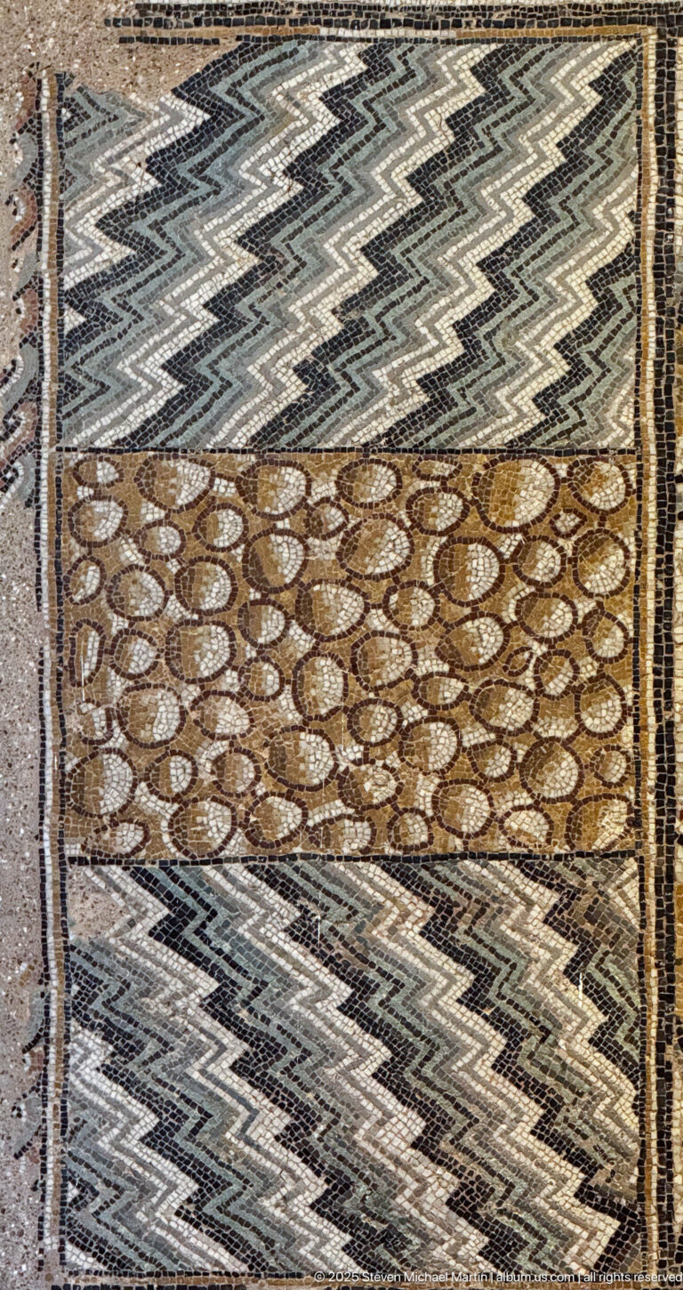 Roman mosaic with black-and-white zigzag bands beside a brown panel filled with repeated oval pebble-like motifs.