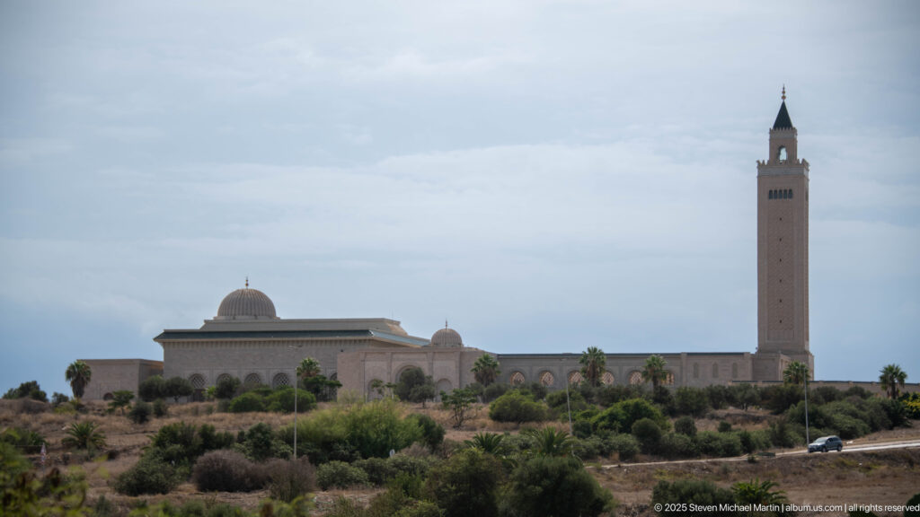Malik ibn Anas Mosque in Carthage with tall square minaret, central dome, arcades, and landscaped foreground.