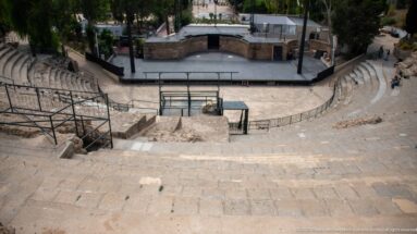 High view down the Roman Theatre of Carthage seating toward the modern stage and performance area.