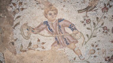 Roman mosaic of a youthful figure in patterned clothing holding a bird among branches and small animals.