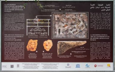 Multilingual panel about the archaic Phoenician necropolis of Carthage with plans, artifacts, and burial photographs.