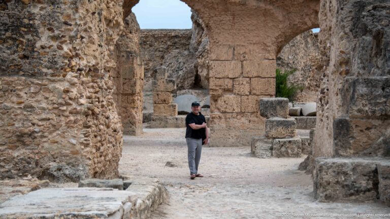 Visitor walking among massive stone arches and piers in the lower ruins of the Baths of Antoninus.