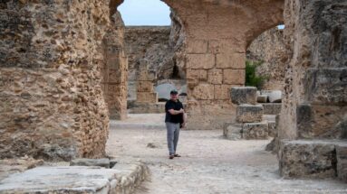 Visitor walking among massive stone arches and piers in the lower ruins of the Baths of Antoninus.