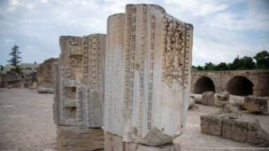 Tall carved marble blocks with Latin inscription fragments, rosettes, moldings, and classical ornament at the Baths of Antoninus.