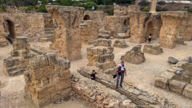 Elevated view of massive stone piers, bases, arches, and visitors within the Baths of Antoninus.