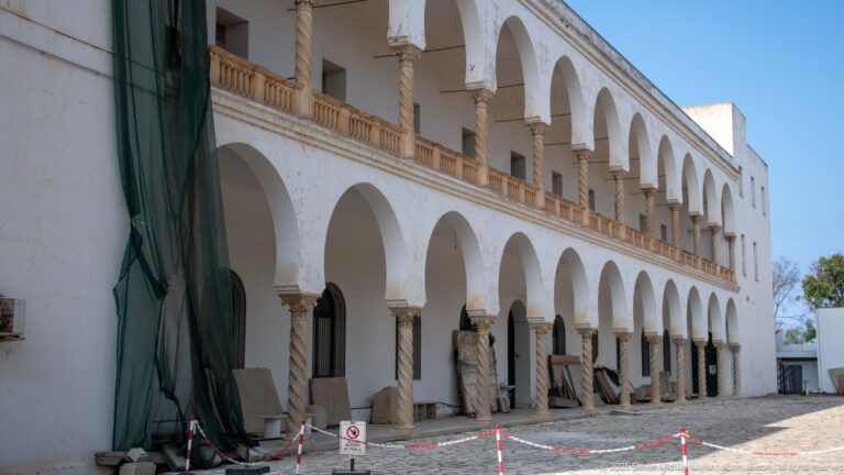 Two-story white arcaded building with repeated rounded arches, slender columns, and temporary conservation barriers at Byrsa Hill.