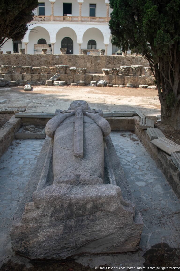 Full-length recumbent stone effigy of a robed cleric lying on a raised memorial at Byrsa Hill.