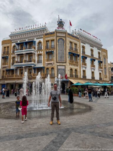 Hotel Royal Victoria behind fountains, café seating, pedestrians, and families in Place de la Victoire, Tunis.