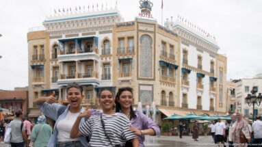 Three smiling visitors pose in a Tunis square with the ornate Hotel Royal Victoria behind them.