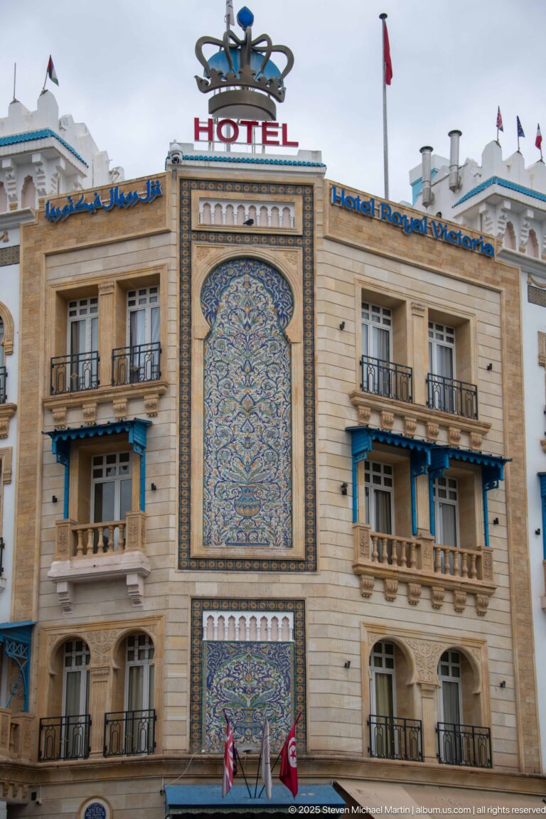 Large blue and ochre ceramic tile panel centered on the Hotel Royal Victoria façade beneath rooftop signage.