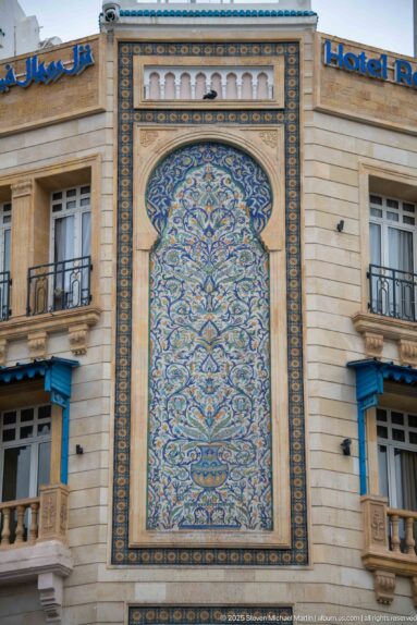 Close-up of ornate blue, turquoise, and ochre ceramic tilework on the Hotel Royal Victoria façade.