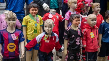 Child mannequins and a young shopper among colorful football shirts and tracksuits in a Tunis shop display.