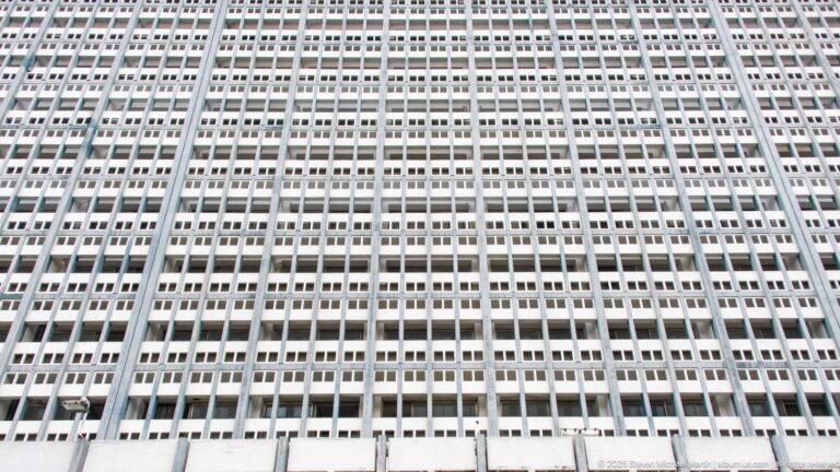 Upward view of a tall modernist Tunis building with a dense white grid of repetitive rectangular windows.
