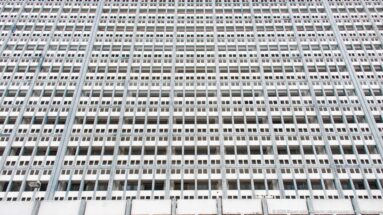 Upward view of a tall modernist Tunis building with a dense white grid of repetitive rectangular windows.