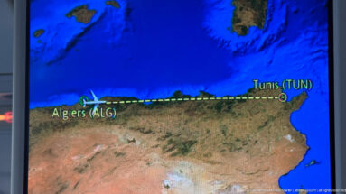 Aircraft map display showing a dotted flight route between Tunis and Algiers along the North African coast.