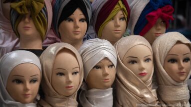 Mannequin heads wearing assorted wrapped headscarves in neutral, black, red, green, and patterned fabrics.