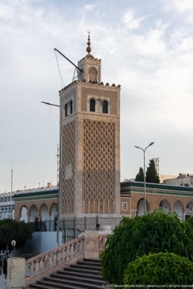 Square Kasbah Mosque minaret with diamond-pattern lattice, paired upper arches, and a small finialed lantern.