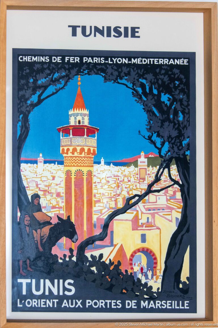 Framed vintage Tunis travel poster with stylized minaret, cityscape, rider, and large French text reading Tunisie and Tunis.