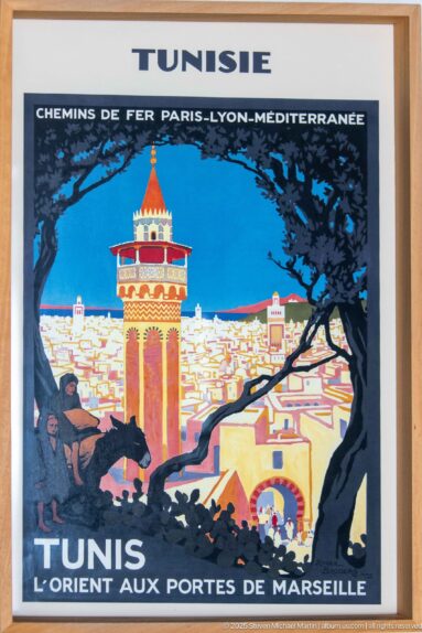 Framed vintage Tunis travel poster with stylized minaret, cityscape, rider, and large French text reading Tunisie and Tunis.