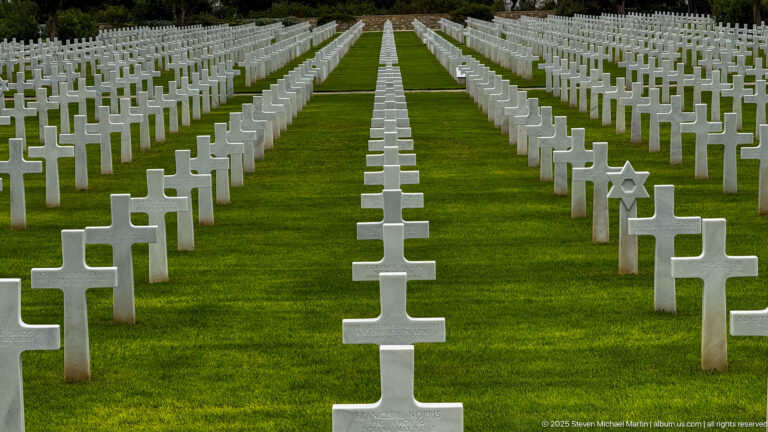 Centered rows of white Latin crosses on grass with one Star of David marker visible at right.
