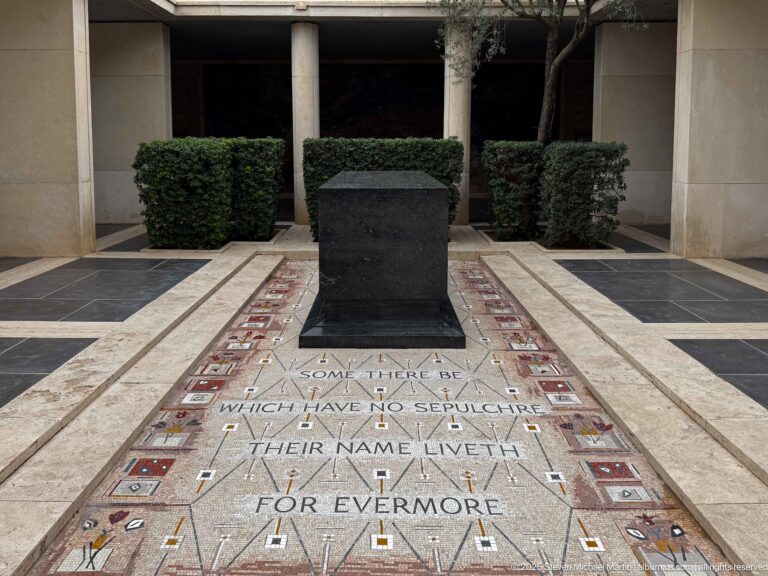 Dark stone pedestal above an inlaid floor inscription reading that those with no sepulchre have names that live forevermore.