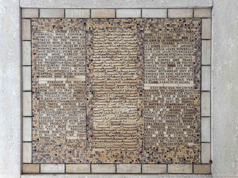 Square mosaic panel with Arabic script in the center and French wartime text on both sides.