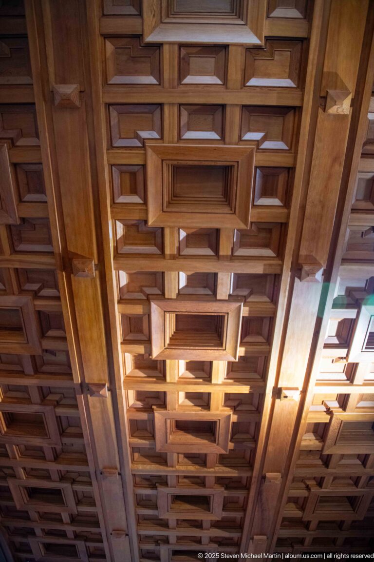 Upward view of an intricate wooden ceiling composed of repeating nested rectangular coffers.