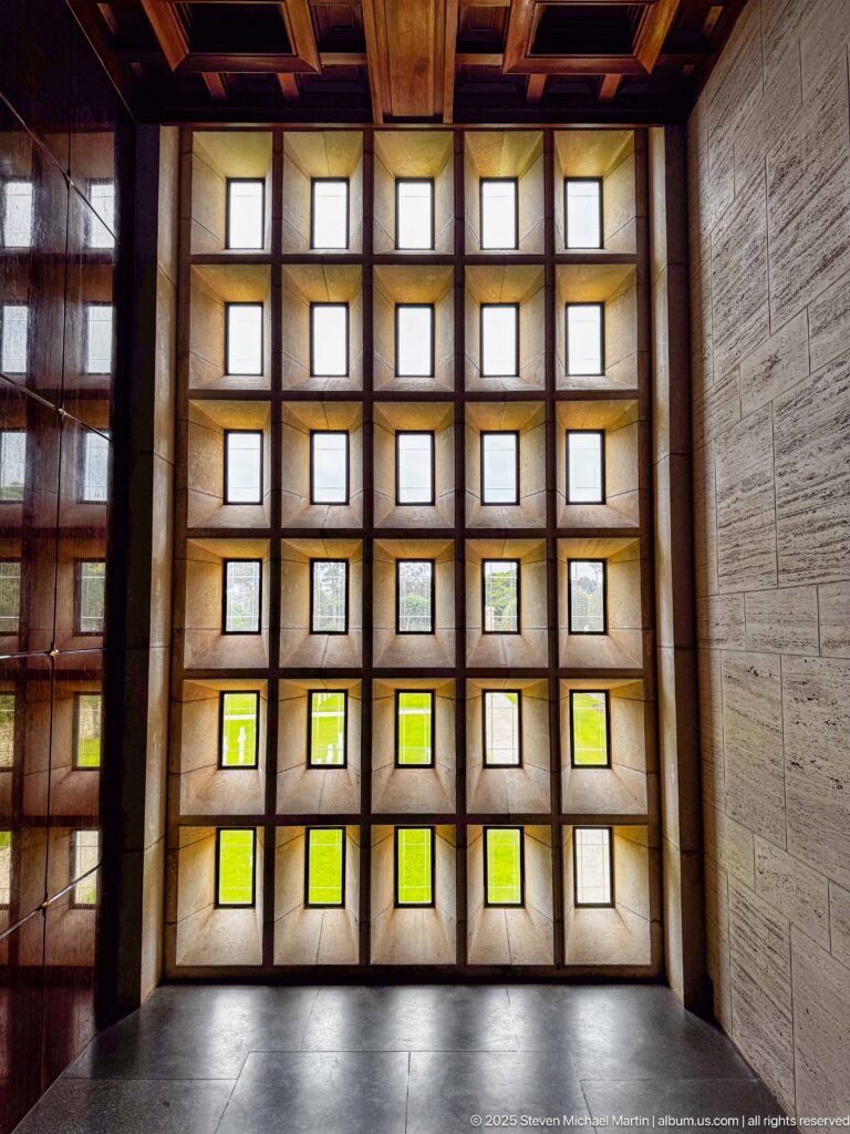 Grid of recessed square translucent windows with pale and green-tinted panes inside the chapel.