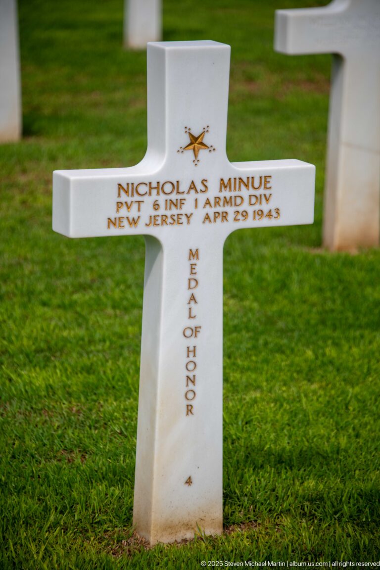 Close white cross for Nicholas Minue with gold Medal of Honor emblem and vertical Medal of Honor lettering.
