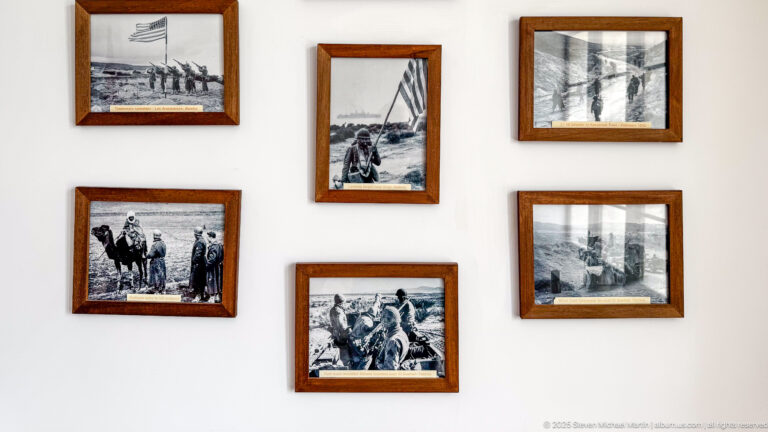 Six framed black-and-white wartime photographs arranged on a white interior wall.