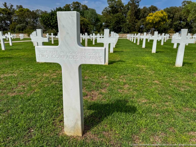 White cross on green grass inscribed Here rest in honored glory two comrades in arms.