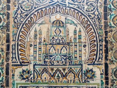 Polychrome tile panel depicting a domed central pavilion with flanking towers, smaller domes, and stylized flowers below.