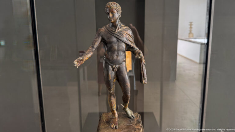 Bronze statuette of Hermes from the Mahdia shipwreck, standing nude with right hand extended and drapery falling from his left shoulder.