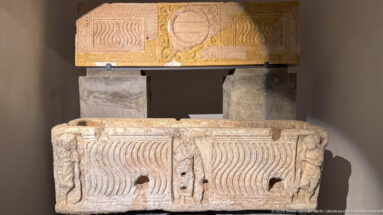Two stacked carved stone blocks with repeated vertical wave patterns below and a large circular medallion on the upper block.