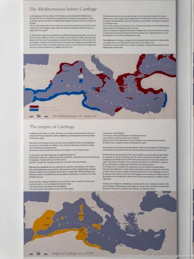 Museum panel with Mediterranean maps showing the origins and territorial expansion of Carthage in contrasting colors.