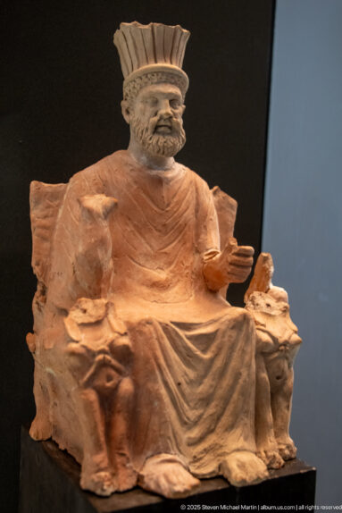 First-century terracotta Baal Hammon from Thinissut seated on a sphinx-flanked throne beneath a high feathered crown.