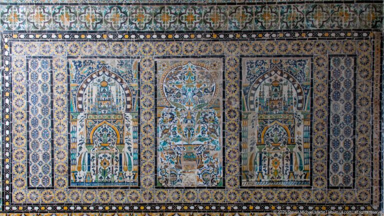 Polychrome tile panel with two matching niche motifs flanking a central floral vase, surrounded by dense geometric borders.