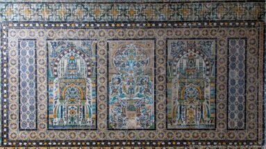 Polychrome tile panel with two matching niche motifs flanking a central floral vase, surrounded by dense geometric borders.
