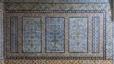 Polychrome tile panel with three arched fields containing floral vases, framed by patterned borders.