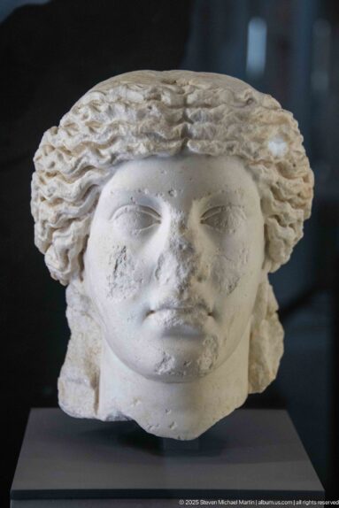 Idealized marble female head with center-parted wavy hair, smooth cheeks, and a calm frontal expression.