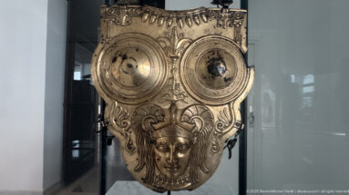 Gilded-bronze Ksour Essef cuirass with two circular chest bosses, helmeted female head, and scrolling vegetal ornament.
