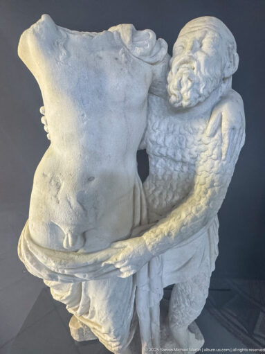 Fragmentary marble group with a human figure pressed beside a large animal head and a thick curved element crossing the front.