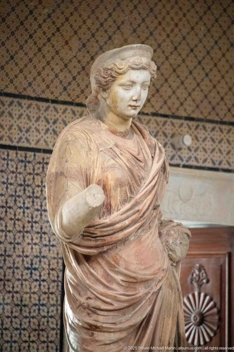 Standing marble woman with layered drapery and extensive surviving reddish pigment on the garments.