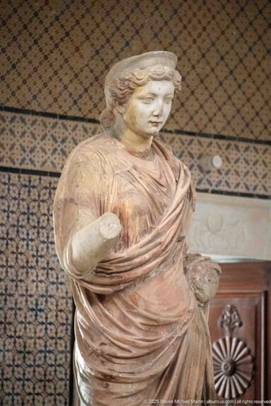 Standing marble woman with layered drapery and extensive surviving reddish pigment on the garments.