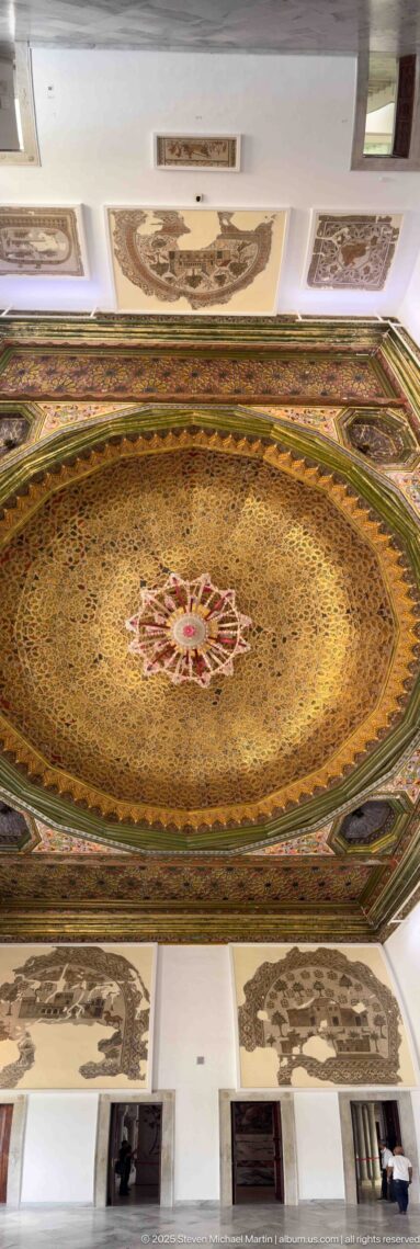 Oblique wide view of the ornate octagonal ceiling above white gallery walls hung with mosaics.