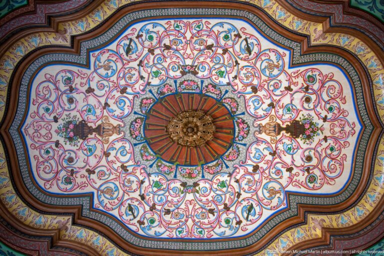 Lobed ceiling panel with central rosette, multicolored scrolling vines, flowers, and layered painted wooden borders.