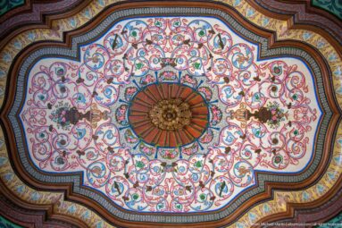 Lobed ceiling panel with central rosette, multicolored scrolling vines, flowers, and layered painted wooden borders.