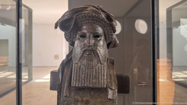 Bronze herm of bearded Dionysos from the Mahdia shipwreck, with elaborate wrapped headdress, long segmented beard, and squared pillar body.